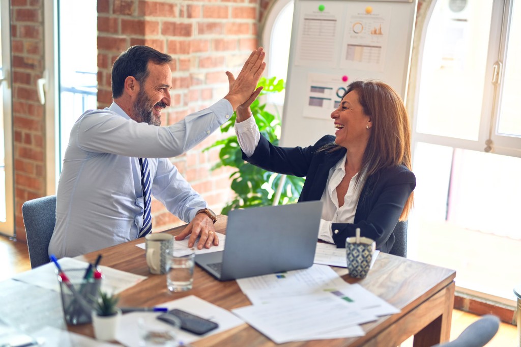 Zwei Kollegen feiern im Büro einen gemeinsamen Erfolg – Teamwork bei Auftrags-Disposition und Außendienst